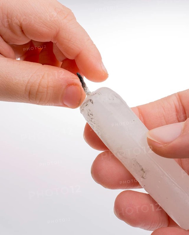 White candle stick in hand on a white background