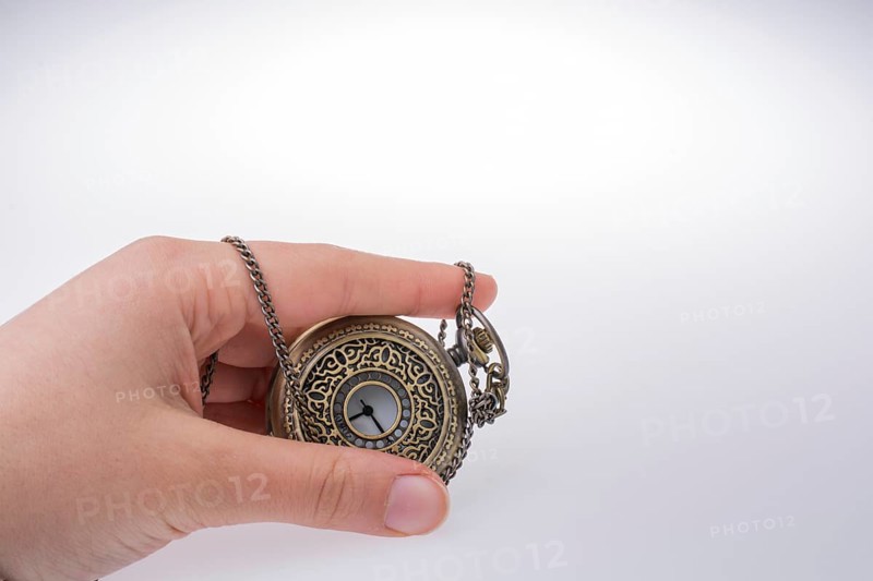 Retro style pocket watch in hand on white background