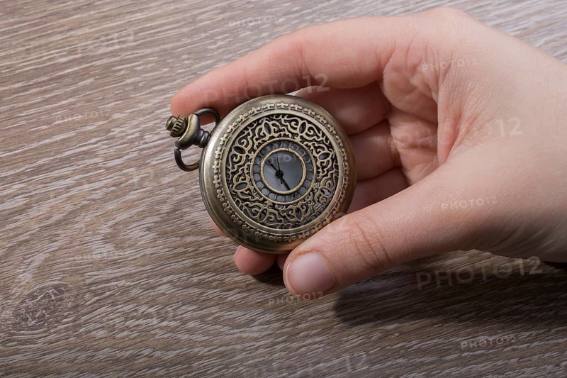 Retro style pocket watch in hand on black background