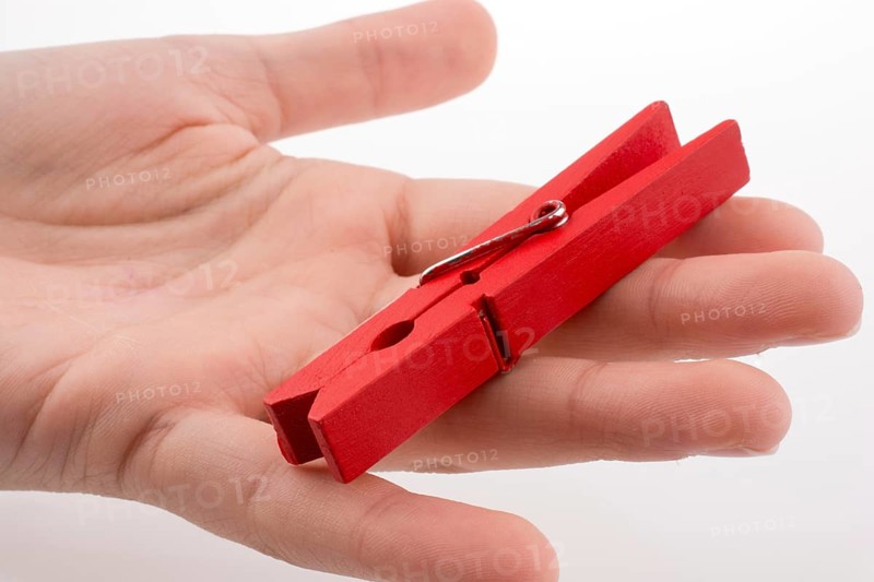 Hand holding a red clothespin on a white background