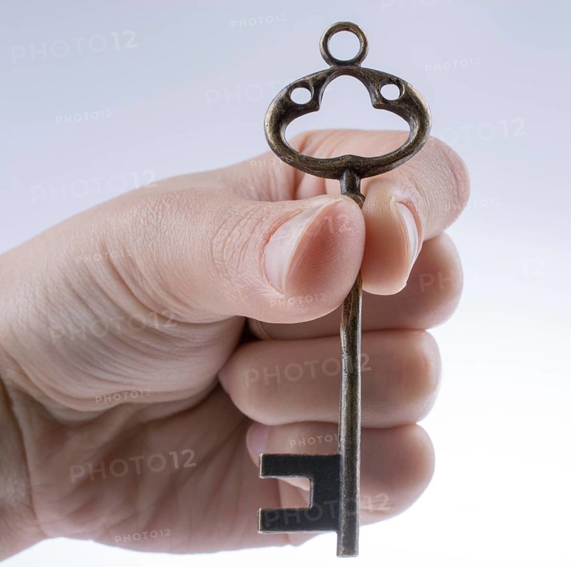Hand holding a retro styled metal key on a white background