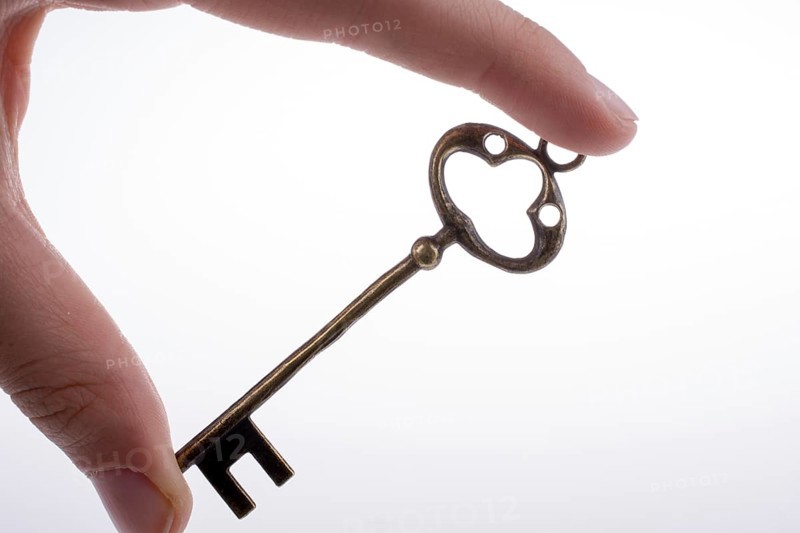 Hand holding a retro styled metal key on a white background