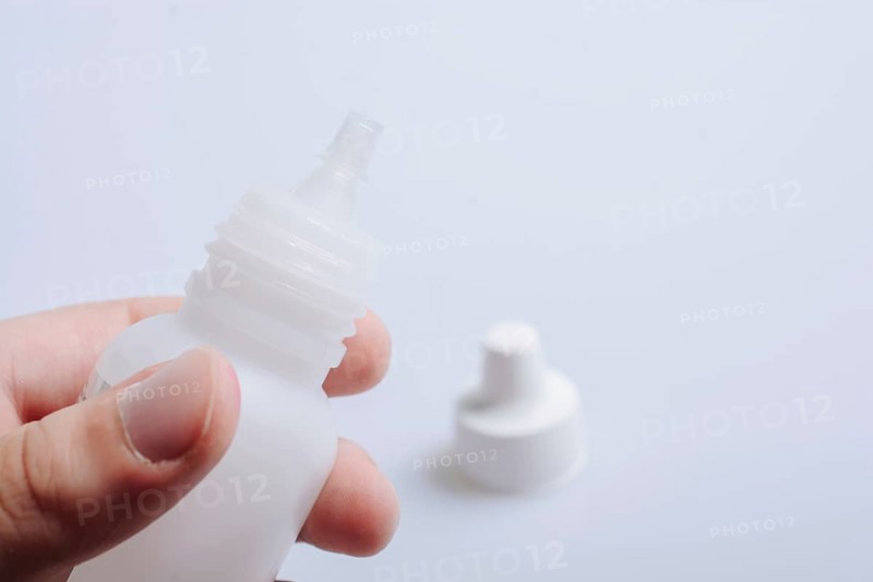 White empty dropper bottle in hand on a white background