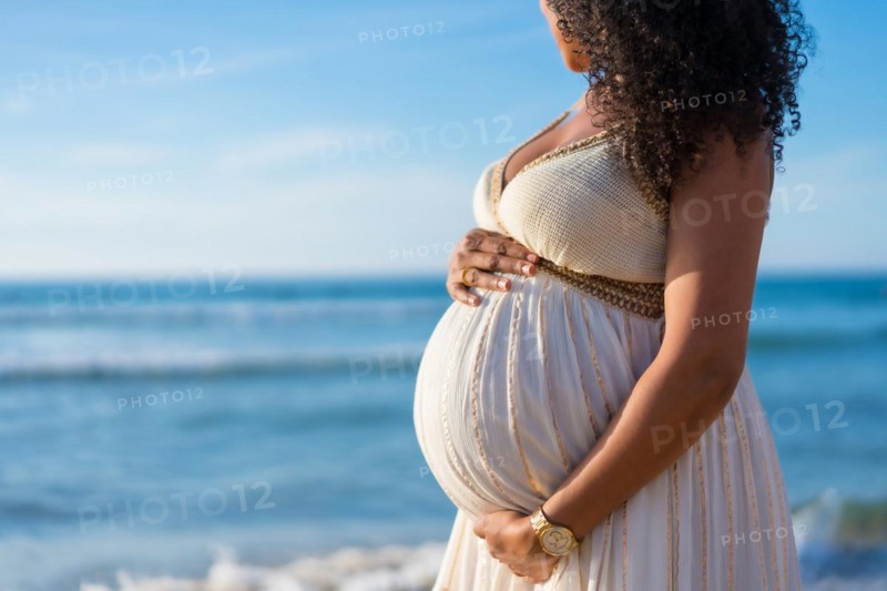 Pregnant maternity latin woman on the beach at sunset