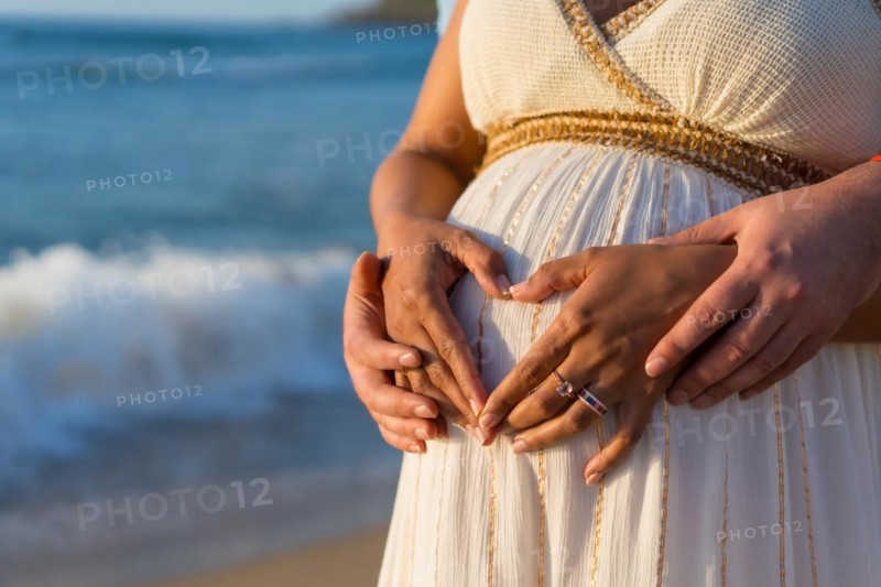 Pregnant maternity latin woman on the beach at sunset