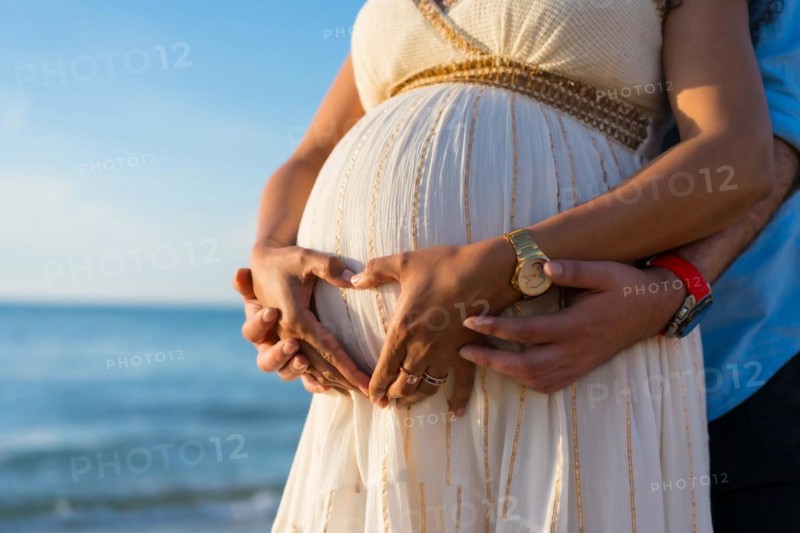 Pregnant maternity latin woman on the beach at sunset