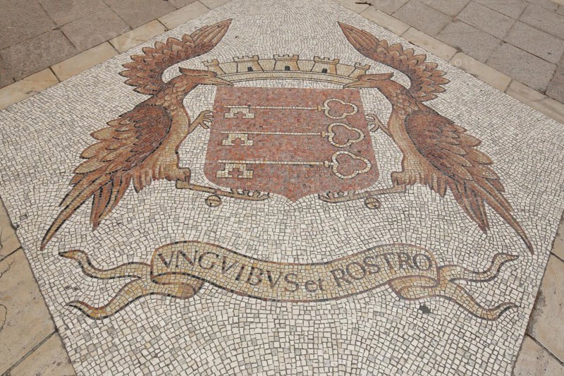 City coat of arms with two bird figures and Latin inscription