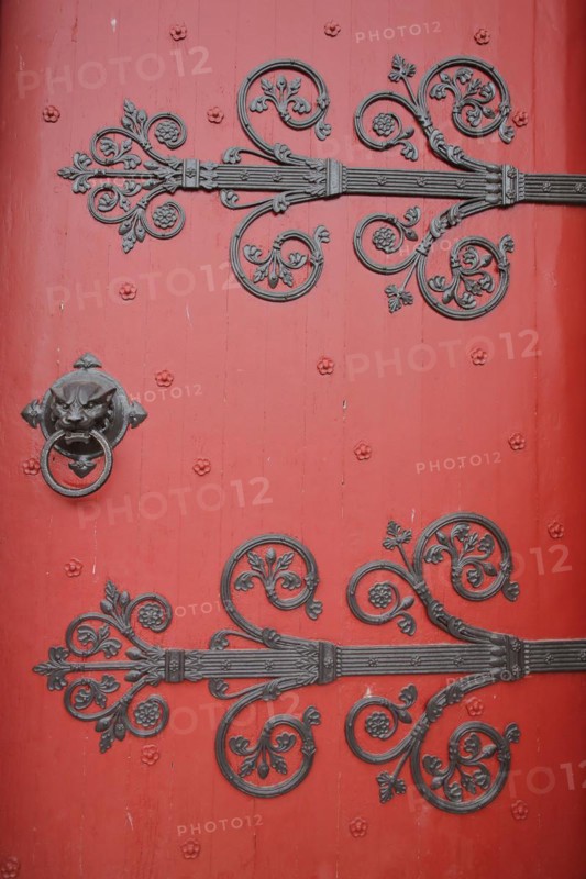 Red church door with fittings and decorations of the Romanesque St Ägidius Abbey Church