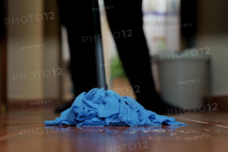 Unidentified woman mopping the floor with a blue mop in close-up