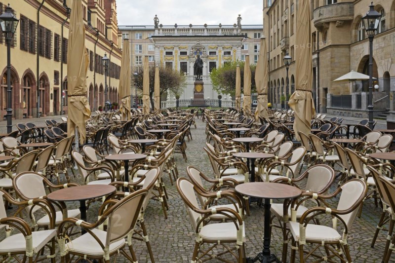 Empty chairs and tables at the Naschmarkt in the early morning with Goethe monument in front of the Old Stock Exchange