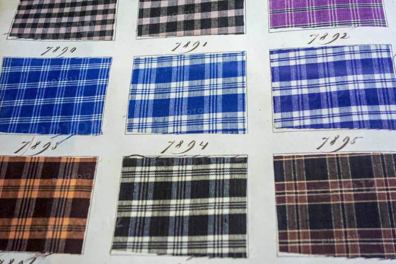 Page in old textile sample book showing chequered fabric samples with different weaving patterns and colour combinations