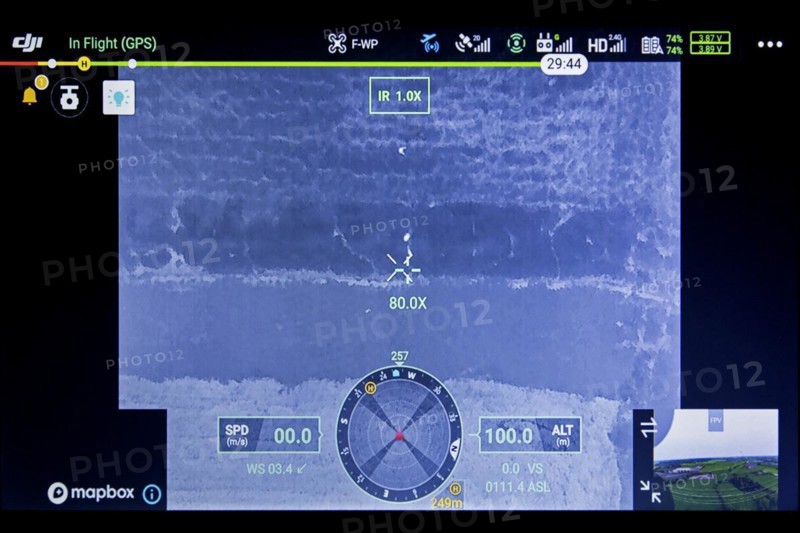 Roe deer fawn located in field on monitor with help of thermal imaging camera mounted on drone flying over meadow before mowing grassland in spring
