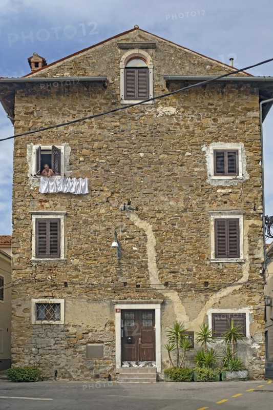 Woman in old house hanging clothes on washing line in the city Koper