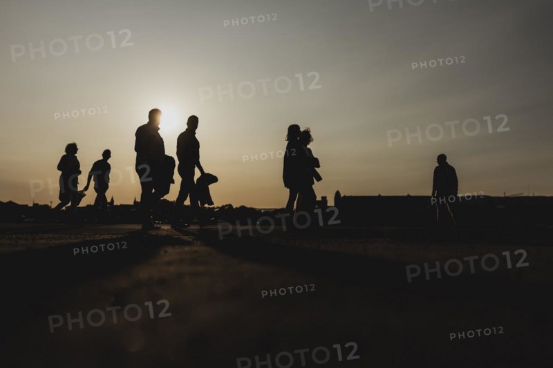 Silhouettes of walkers stand out against the setting sun on the harbour promenade in Oslo