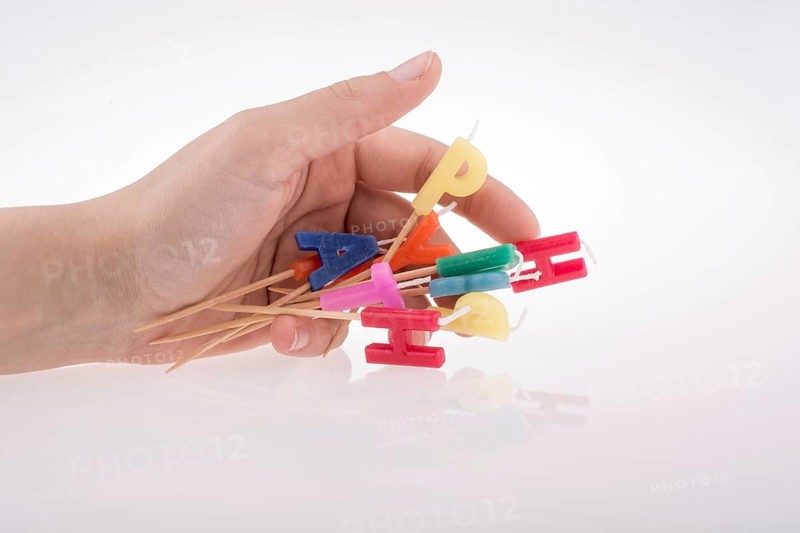 Letters made of candles on sticks falling off hand