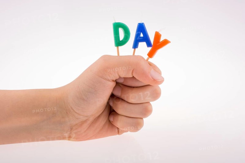 Color candles on sticks in hand write the word day