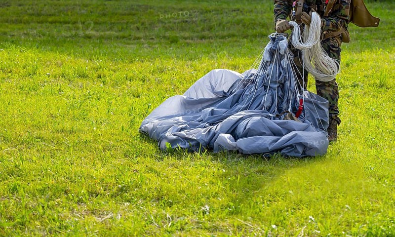 Military Parachuter Standing on the Grass with His Parachute in Switzerland
