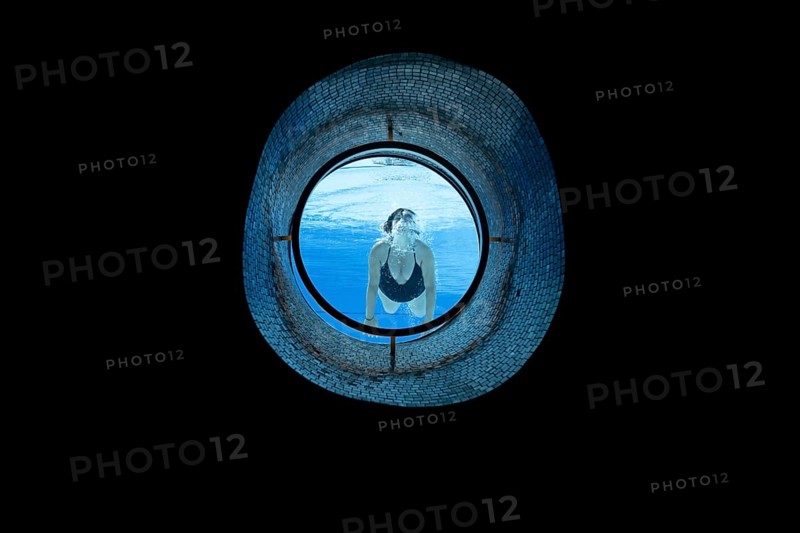 Woman Swimming in the Ship Porthole in Underwater in Swimming Pool in a Sunny Day in Switzerland