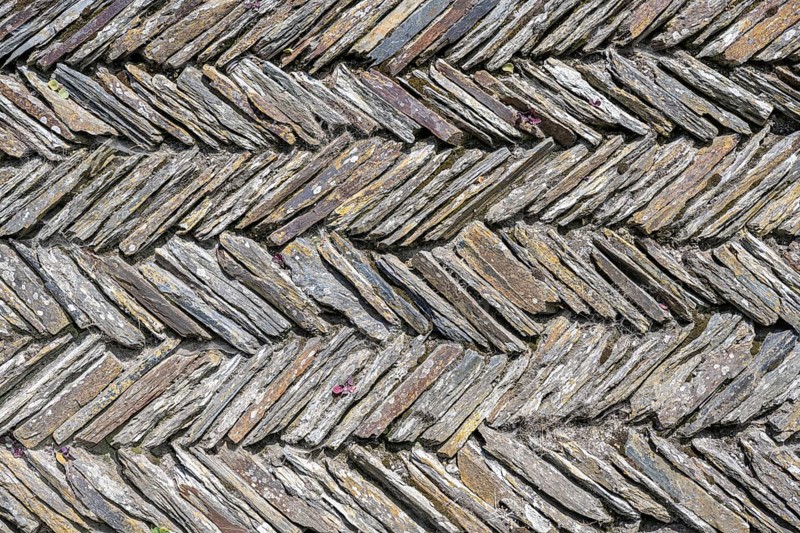 Slate slabs stacked in a herringbone pattern to form a wall