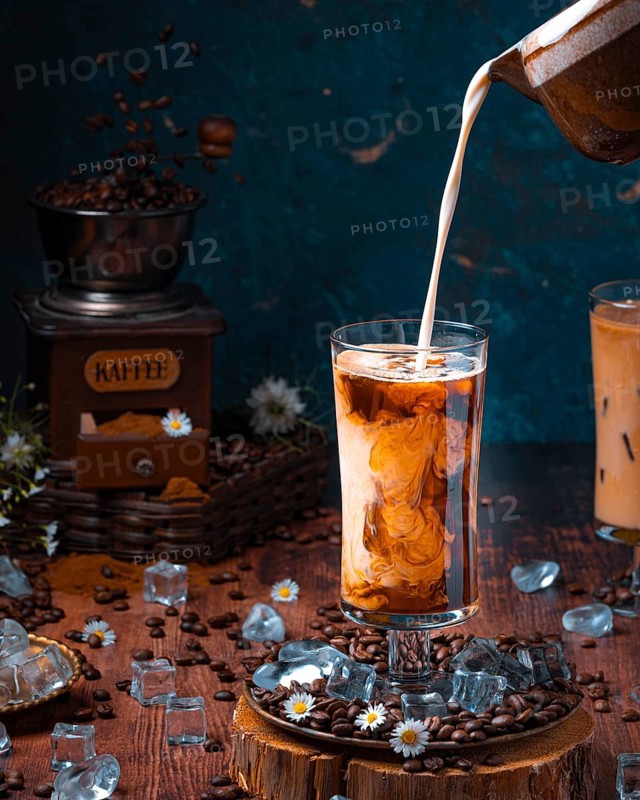 Milk is poured into glass with cold coffee