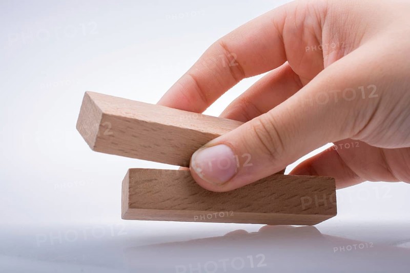 Hand holding wooden domino on a white background