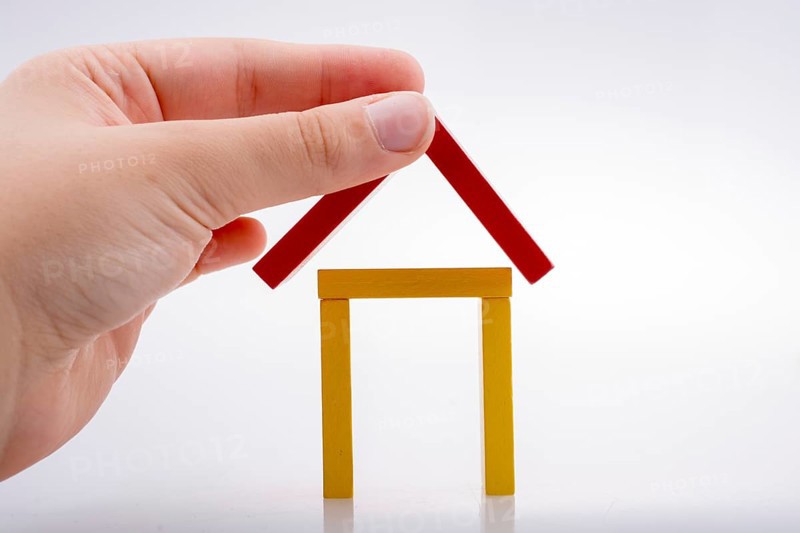 Hand holding domino pieces forming a house shape