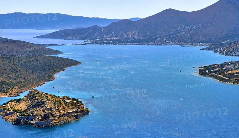 Aerial view of clear sea waters of harbor between Spinalonga island and peninsula
