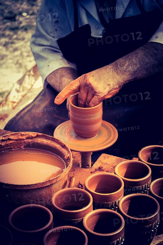Potter`s hands shaping up the clay of the pot
