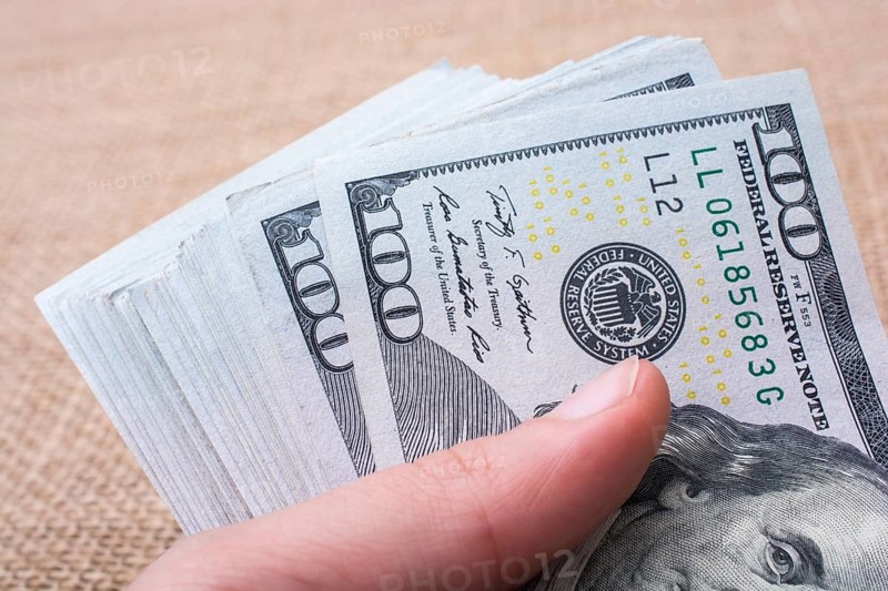 Hand holding banknote bundle of US dollar on a linen canvas background