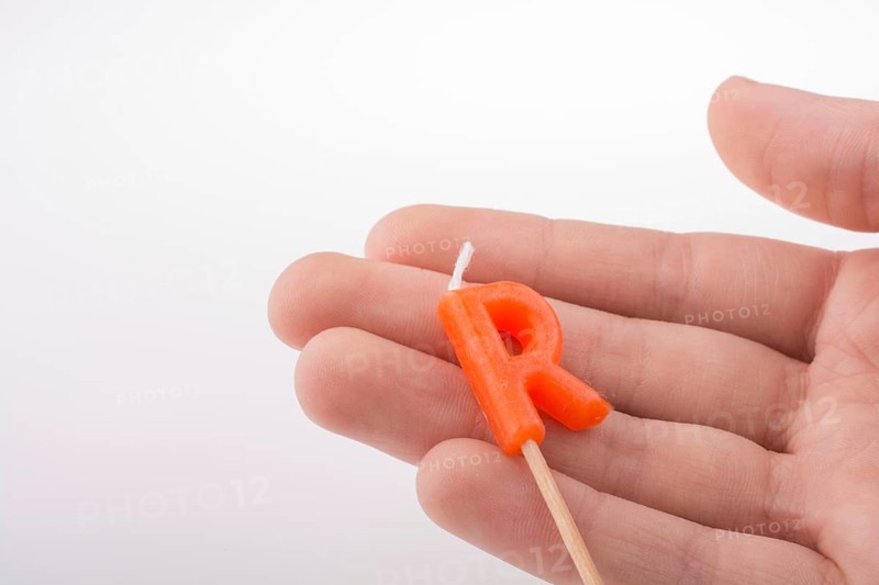Color candle in hand on sticks writes the letter R