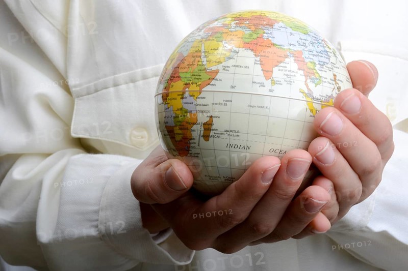 Child holding a small model globe in hand on white background
