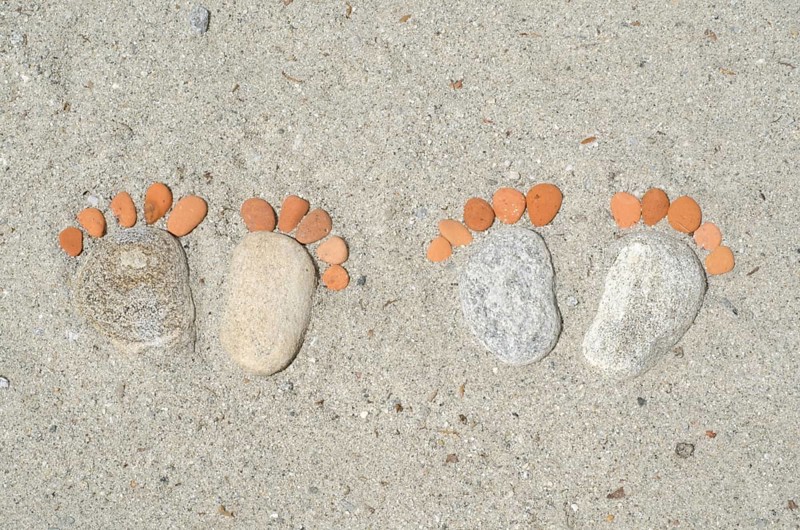 Couple of Footprints Made of Stones in the Sand