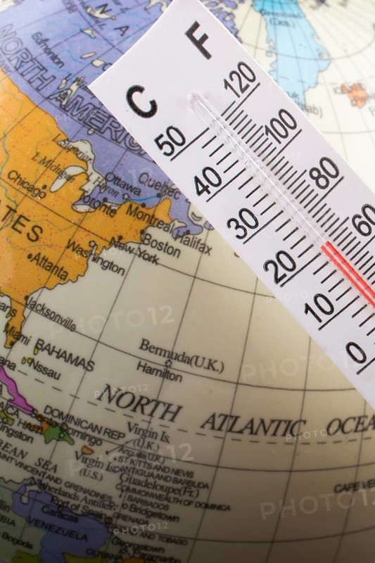 Hand placing a thermometer on a little model globe