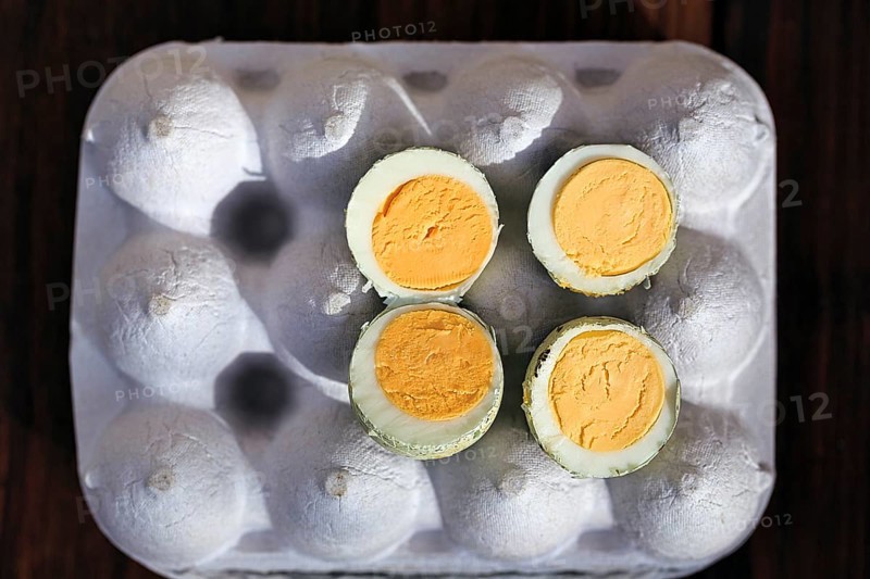 Cooked halved quail eggs on an egg carton