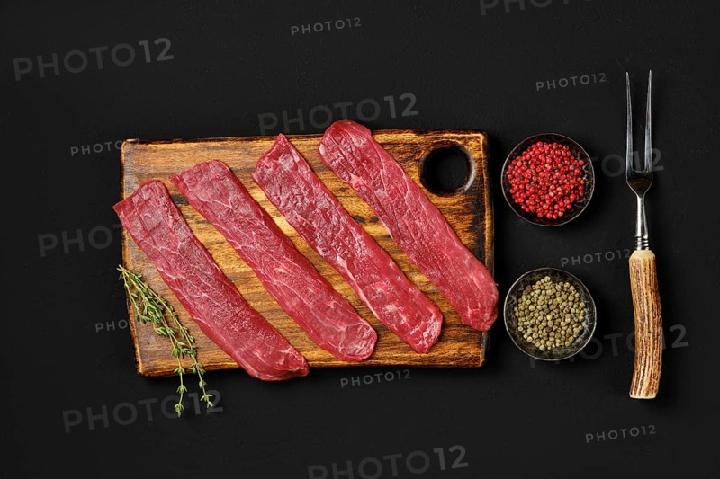 Top view of raw beef strips on black background