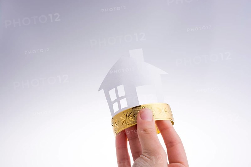 Paper house with a golden bracelet on a white background