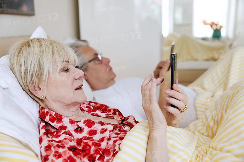 Elderly couple lying in bed together in their bedroom