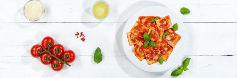 Ravioli Italian pasta eat lunch dish with plate in tomato sauce from above on wooden board Panorama in Stuttgart