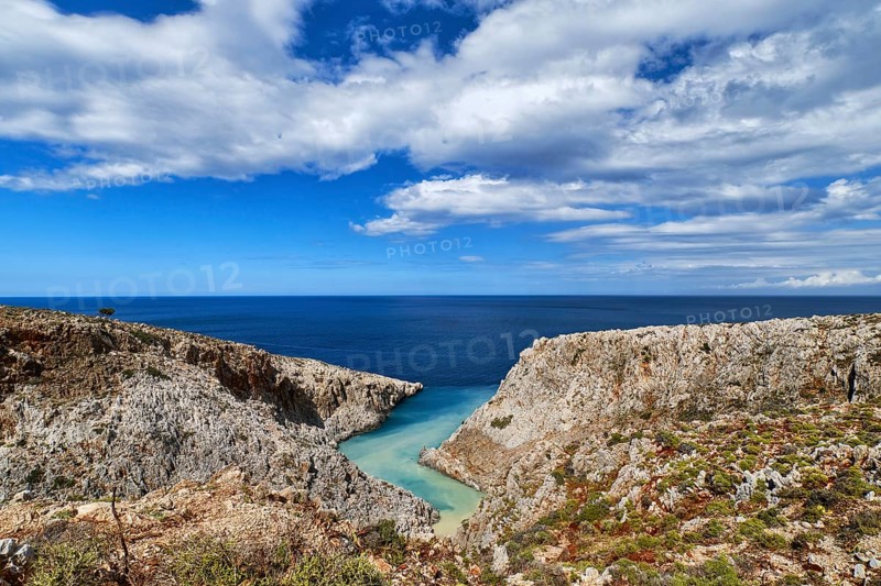 Beautiful view of z-shaped cove or harbor in typical hills of Crete landscape. Clear blue sky and beautiful clouds on sunny day. Azure sea waters. Stefanou beach