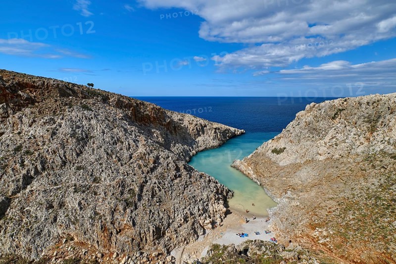 Beautiful view of z-shaped cove or lagoon in typical hills of Crete landscape. Clear blue sky and beautiful clouds on sunny day. Azure sea waters. Stefanou beach
