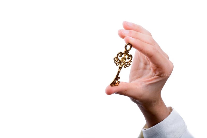 Hand holding a retro styled metal key on a white background