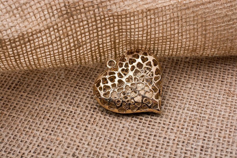 Heart shaped gold color metal object on canvas