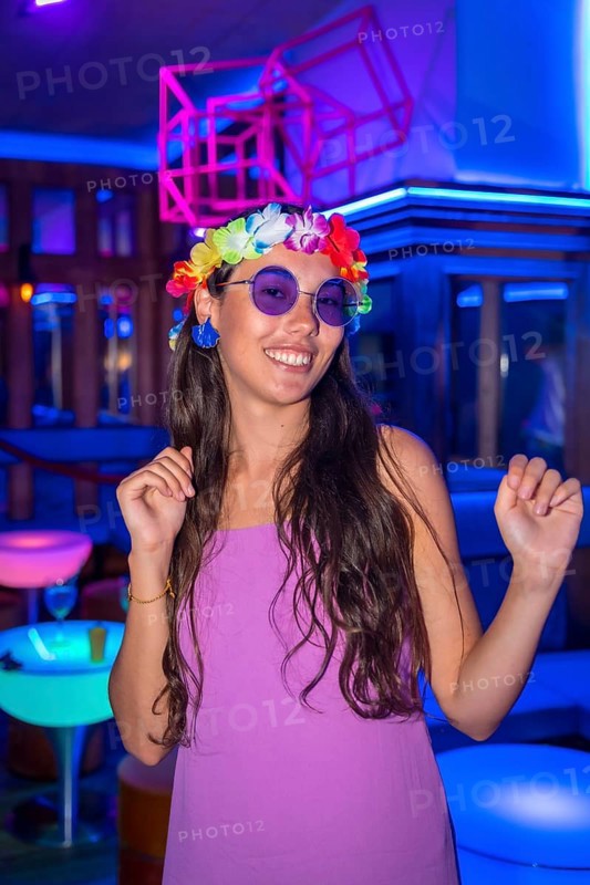 Brunette woman dancing at a night club party in purple glasses at a pub party
