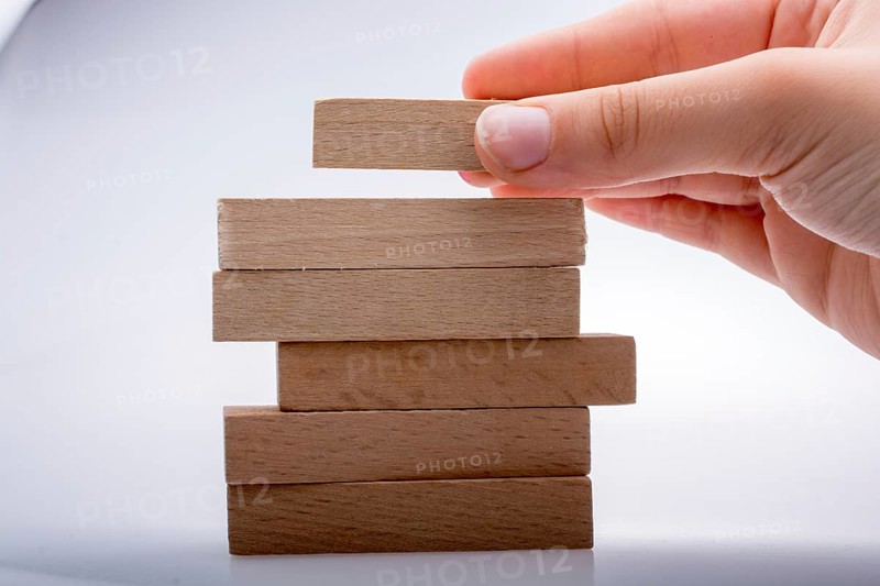 Hand holding wooden domino on a white background