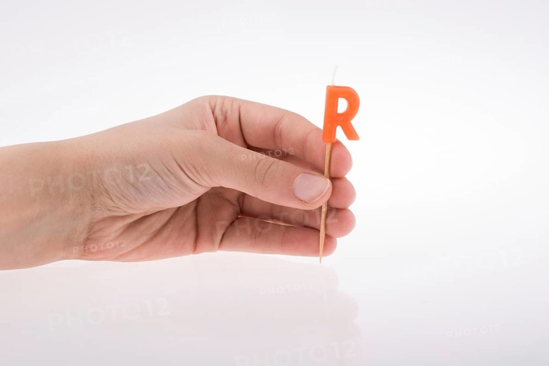 Color candle in hand on sticks writes the letter R