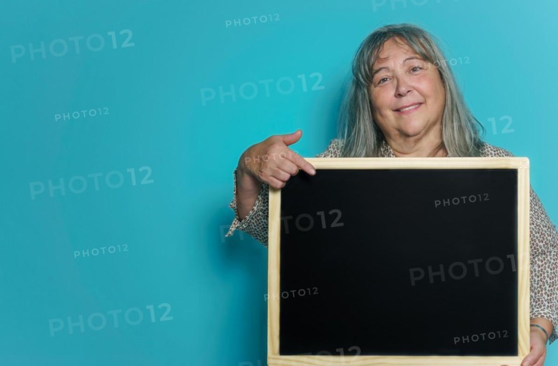 Older white-haired woman holding a blackboard with space for copying text