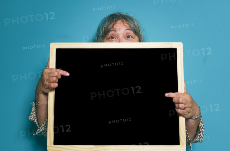 Older white-haired woman holding a blackboard with space for copying text