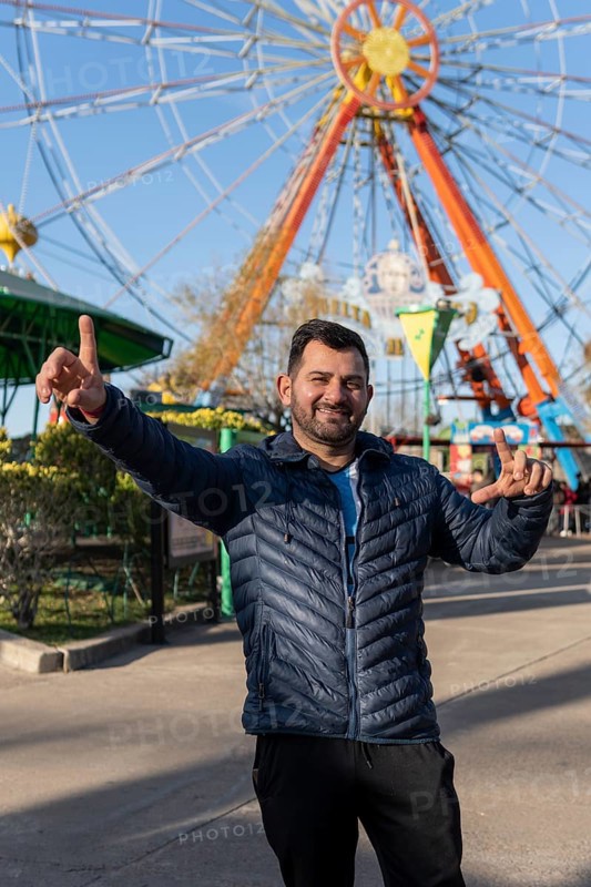 Portrait of latino man in an amusement park posing happy with the ferris wheel in the background