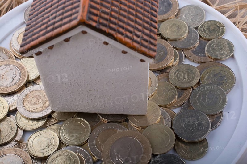 Turkish Lira coins by the side of a model house on white background