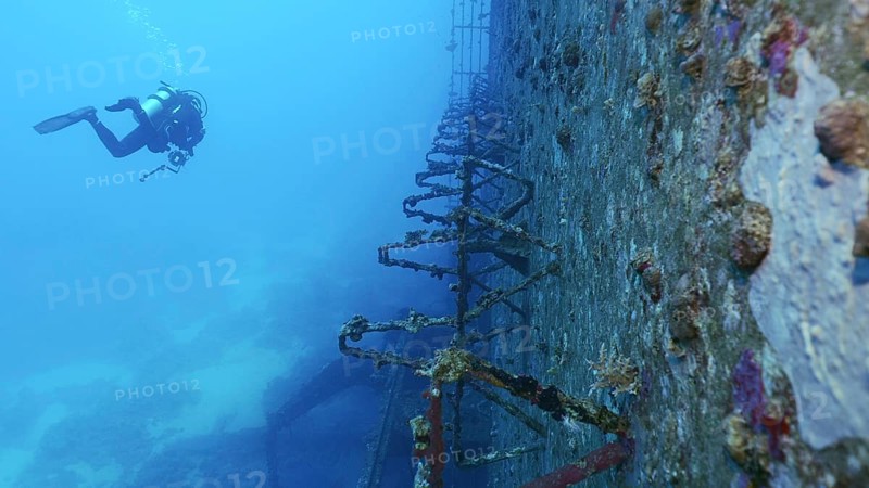Scuba diver swim along deck of ferry Salem Express shipwreck approaching the ship's superstructure